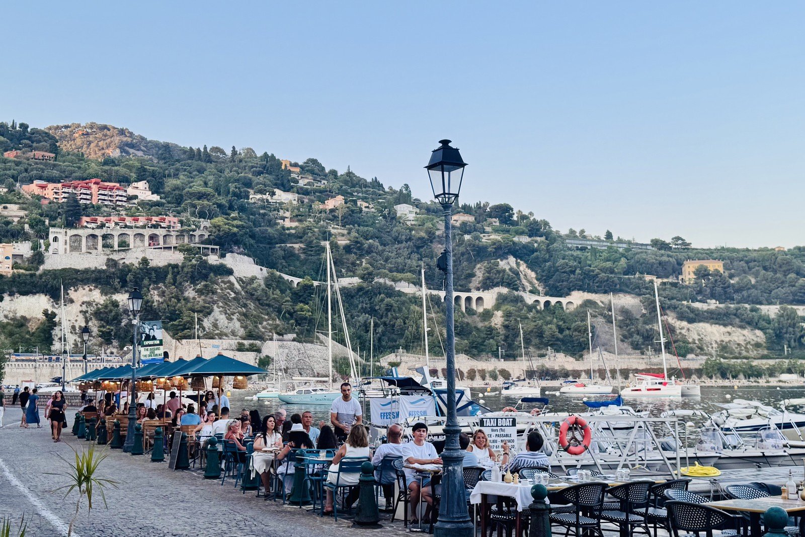 Les terrasses de restaurants du port de Villefranche-sur-Mer un soir d’août, bateaux au mouillage