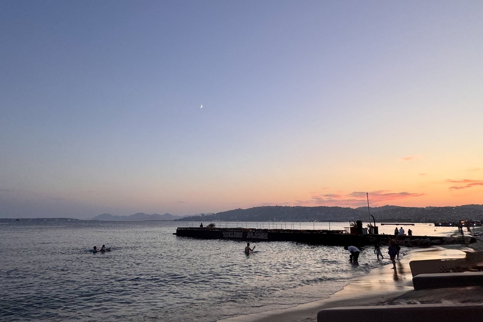 Swimmers at sunset near a pier